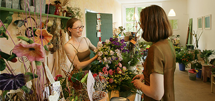 Verkäuferin präsentiert im Laden einer Kundineinen tollen Bluemnstrauß