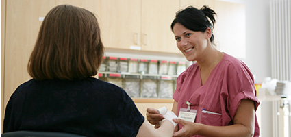 Sympathische Krankenschwester legt einen Verband ums Handgelenk der Patientin.