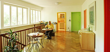 Älterer Mann sitzt am Tischchen im schönen Gästehaus und trinkt einen Tee.