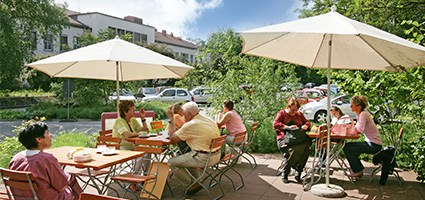 Gäste sitzen auf der sonnigen Terasse des Cafés.
